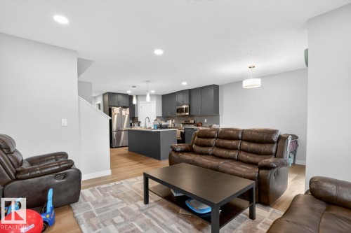 Open-concept living area featuring light wood-finish flooring, recessed lighting, and a contemporary kitchen - 3214 9 Street, Edmonton, AB - Indoor Photo Showing Living Room