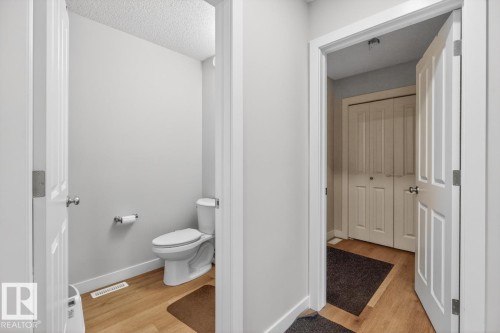 Powder room featuring light wood-finish flooring, a white toilet, and light gray walls - 3214 9 Street, Edmonton, AB - Indoor Photo Showing Bathroom