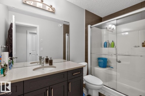 Bathroom featuring a single vanity with dark wood-finish cabinetry and a light-toned countertop, a built-in rectangular sink, and a large wall-mounted mirror - 3214 9 Street, Edmonton, AB - Indoor Photo Showing Bathroom