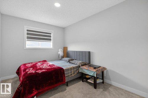 Interior room featuring light gray wall paint, a single window with horizontal blinds, overhead ceiling lighting, and carpeted flooring - 3214 9 Street, Edmonton, AB - Indoor Photo Showing Bedroom