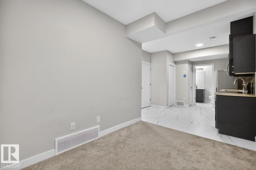 Open-concept space featuring neutral gray walls and plush carpeting, transitioning to white marble-look tile flooring - 3214 9 Street, Edmonton, AB - Indoor Photo Showing Other Room