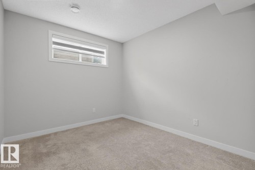 Carpeted room featuring a white-trimmed window with horizontal blinds, light grey wall paint, white baseboards, and a textured white ceiling - 3214 9 Street, Edmonton, AB - Indoor Photo Showing Other Room