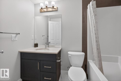 Bathroom featuring a dark wood-finish vanity with a light-toned countertop, integrated sink, and brushed nickel hardware - 3214 9 Street, Edmonton, AB - Indoor Photo Showing Bathroom