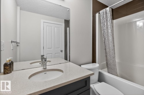 Bathroom vanity featuring a light-toned countertop, undermount sink, and chrome faucet - 3214 9 Street, Edmonton, AB - Indoor Photo Showing Bathroom