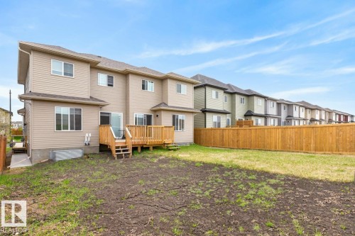 Rear exterior with wood decking and steps, featuring beige vinyl siding - 3214 9 Street, Edmonton, AB - Outdoor With Exterior