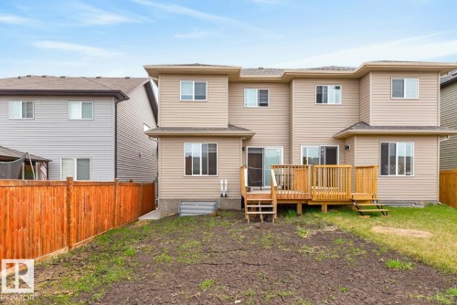 Rear exterior featuring a spacious wood deck, light beige siding, multiple windows, and a brown privacy fence - 3214 9 Street, Edmonton, AB - Outdoor With Deck Patio Veranda With Exterior
