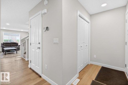 Bright entryway featuring wood-finish flooring, white baseboards, a white interior door, and a bi-fold closet - 3214 9 Street, Edmonton, AB - Indoor Photo Showing Other Room