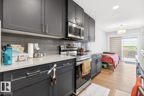 Modern kitchen featuring dark grey cabinetry, light-toned countertops, and a subway tile backsplash - 3214 9 Street, Edmonton, AB - Indoor Photo Showing Kitchen With Upgraded Kitchen