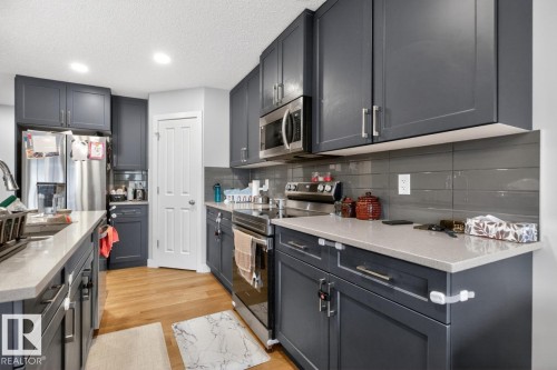 Contemporary kitchen featuring shaker-style cabinetry, light-toned countertops, a stainless steel appliance suite, and a gray subway tile backsplash - 3214 9 Street, Edmonton, AB - Indoor Photo Showing Kitchen With Stainless Steel Kitchen With Upgraded Kitchen