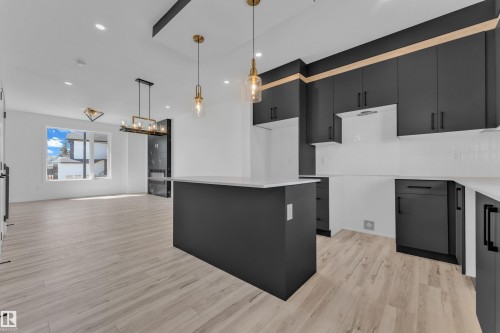 Kitchen and living area featuring light wood-finish flooring, white walls, recessed lighting, and a kitchen island with a light-toned countertop - 171 Graybriar Drive, Stony Plain, AB - Indoor Photo Showing Kitchen