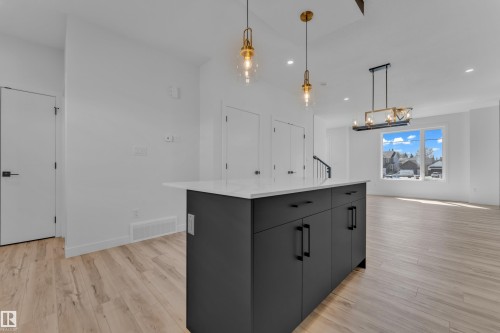 Kitchen island featuring a white countertop, matte black cabinetry, and two brass pendant lights - 171 Graybriar Drive, Stony Plain, AB - Indoor