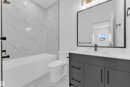 Modern bathroom featuring a built-in tub with white marble-look tile surround and matte black fixtures - 171 Graybriar Drive, Stony Plain, AB - Indoor Photo Showing Bathroom