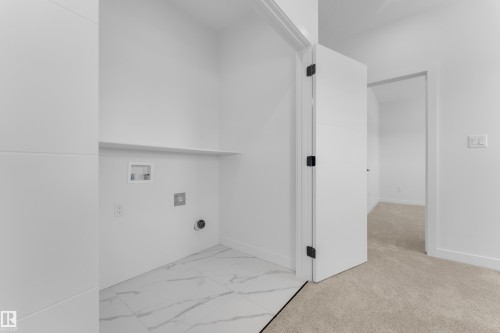 Dedicated laundry area featuring a built-in shelf, plumbing hookups, and a contemporary white tile floor with gray veining - 171 Graybriar Drive, Stony Plain, AB - Indoor Photo Showing Other Room