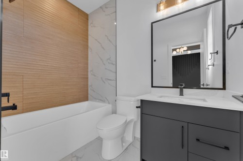 Modern bathroom featuring a freestanding tub with textured wood-finish wall tiles and marble-look wall tiles - 171 Graybriar Drive, Stony Plain, AB - Indoor Photo Showing Bathroom