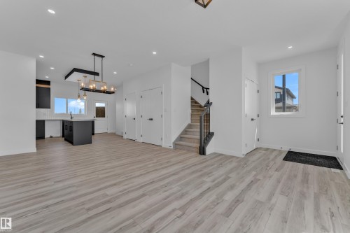 Open-concept living area featuring light wood-finish flooring, recessed lighting, and a modern kitchen with dark cabinetry and an island - 171 Graybriar Drive, Stony Plain, AB - Indoor Photo Showing Other Room