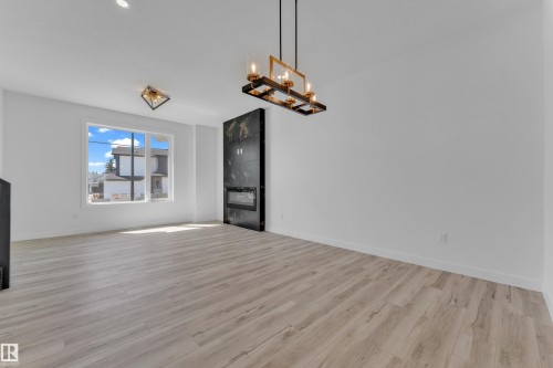 Contemporary living area featuring wide-plank wood-finish flooring and a large window providing abundant natural light - 171 Graybriar Drive, Stony Plain, AB - Indoor Photo Showing Other Room