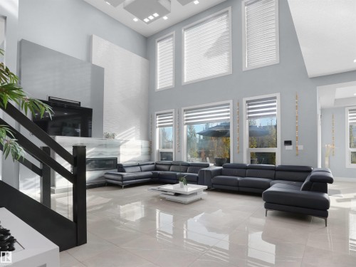 Spacious double-height living area featuring large windows with blinds, a modern fireplace with a light-toned surround, polished tile flooring, and a contemporary black staircase with glass panels - 913 Wood Place, Edmonton, AB - Indoor Photo Showing Living Room