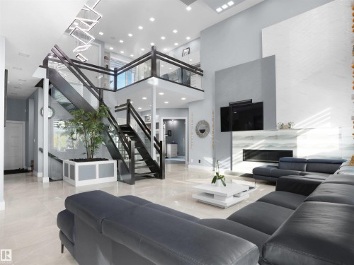 Double-height living space featuring large format tile flooring and a multi-level staircase with glass railings - 913 Wood Place, Edmonton, AB - Indoor