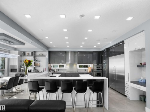 Modern kitchen featuring an expansive island with seating, high-gloss cabinetry, stainless steel appliances, integrated cooktop, and recessed lighting - 913 Wood Place, Edmonton, AB - Indoor Photo Showing Kitchen With Upgraded Kitchen