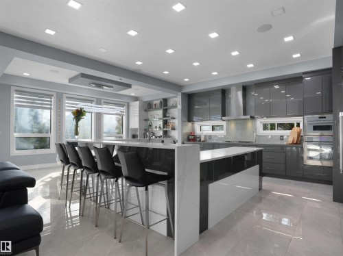 Contemporary kitchen featuring a large island with waterfall countertop, high-gloss cabinetry, stainless steel appliances, a tile backsplash, and recessed lighting - 913 Wood Place, Edmonton, AB - Indoor