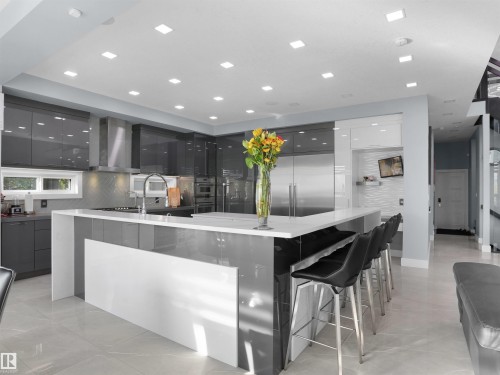 Modern kitchen featuring a large island with white countertops, gray cabinetry, stainless steel appliances, and recessed lighting - 913 Wood Place, Edmonton, AB - Indoor