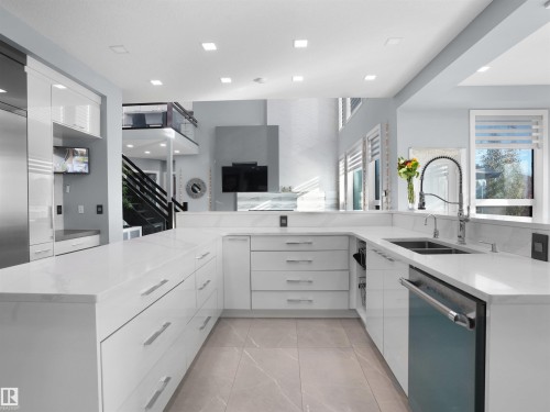 Modern kitchen featuring white cabinetry, light-toned countertops, and a dual basin sink with a gooseneck faucet - 913 Wood Place, Edmonton, AB - Indoor Photo Showing Kitchen With Double Sink With Upgraded Kitchen