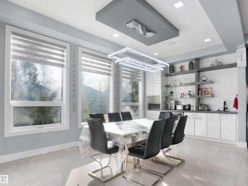 Dining area with porcelain tile flooring, multiple large windows, and a multi-tiered crystal chandelier - 913 Wood Place, Edmonton, AB - Indoor Photo Showing Dining Room