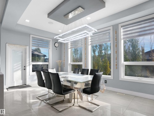 Spacious dining area featuring large windows with modern window treatments, recessed lighting, a contemporary chandelier, and polished tile flooring - 913 Wood Place, Edmonton, AB - Indoor Photo Showing Dining Room