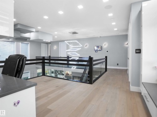 Open-concept upper level featuring light wood-finish flooring and a glass and black metal railing system - 913 Wood Place, Edmonton, AB - Indoor