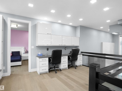 Dedicated workspace featuring two built-in desks with stone-finish countertops, white cabinetry, and overhead storage - 913 Wood Place, Edmonton, AB - Indoor
