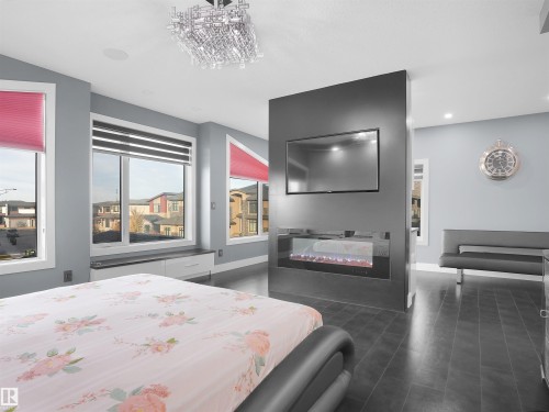 Accent wall with integrated fireplace and wall-mounted television - 913 Wood Place, Edmonton, AB - Indoor Photo Showing Bedroom