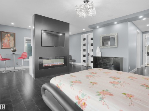 Central partial wall with an integrated electric fireplace and mounted television - 913 Wood Place, Edmonton, AB - Indoor Photo Showing Bedroom With Fireplace