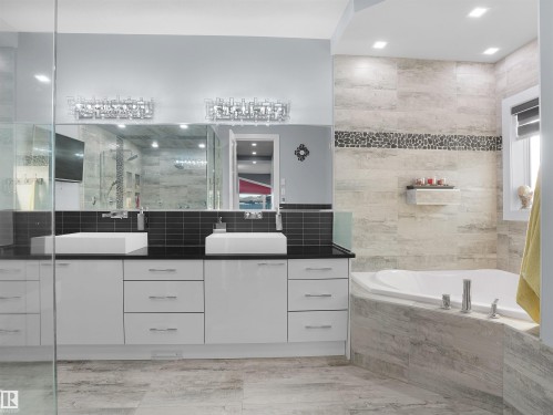 Bathroom featuring a corner soaking tub, a dual vanity with vessel sinks, and an expansive mirror - 913 Wood Place, Edmonton, AB - Indoor Photo Showing Bathroom