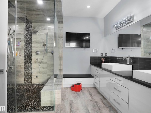 Spacious bath featuring a walk-in shower with pebble tile flooring and a built-in bench - 913 Wood Place, Edmonton, AB - Indoor Photo Showing Bathroom