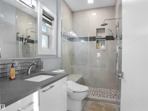 Modern bathroom featuring a glass-enclosed shower with pebble-tile flooring, a built-in shower bench, and recessed shelving - 913 Wood Place, Edmonton, AB - Indoor Photo Showing Bathroom