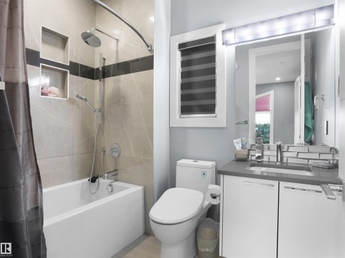 Bathroom featuring a tub/shower combination with rainfall showerhead, tiled walls with recessed niches, and a sleek vanity with an integrated sink - 913 Wood Place, Edmonton, AB - Indoor Photo Showing Bathroom