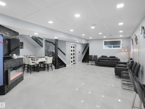 Spacious room featuring light-toned tile flooring, recessed lighting, and a modern electric fireplace with a stacked stone facade - 913 Wood Place, Edmonton, AB - Indoor