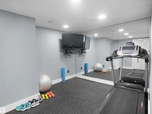 Dedicated fitness space featuring rubberized flooring, a full-wall mirror, recessed lighting, and wall-mounted television - 913 Wood Place, Edmonton, AB - Indoor Photo Showing Gym Room