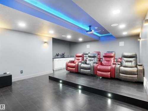 Dedicated home theater featuring a raised viewing platform with integrated lighting, a ceiling-mounted projector, and recessed ceiling speakers - 913 Wood Place, Edmonton, AB - Indoor