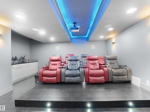 Dedicated home theater featuring tiered seating, recessed ceiling lighting, a built-in projector, and a wet bar with cabinetry and a countertop - 913 Wood Place, Edmonton, AB - Indoor