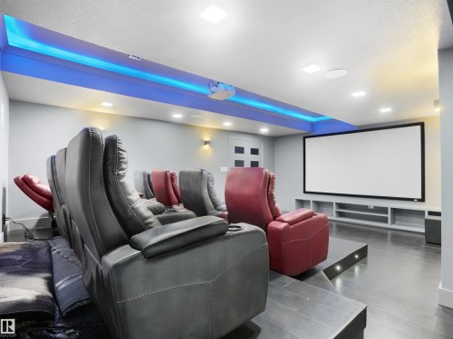 Dedicated home theater featuring tiered flooring, integrated projection screen, built-in shelving, recessed ceiling lighting, and blue accent lighting - 913 Wood Place, Edmonton, AB - Indoor Photo Showing Other Room