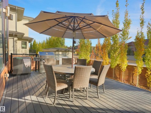 Expansive outdoor deck featuring wood-finish flooring, a built-in barbecue grill, a patio umbrella, and perimeter trees - 913 Wood Place, Edmonton, AB - Outdoor With Deck Patio Veranda