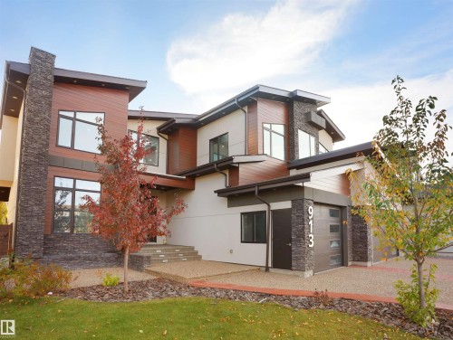 Contemporary exterior featuring multi-level architecture, wood-finish siding, stone accents, expansive windows, and a modern garage door - 913 Wood Place, Edmonton, AB - Outdoor