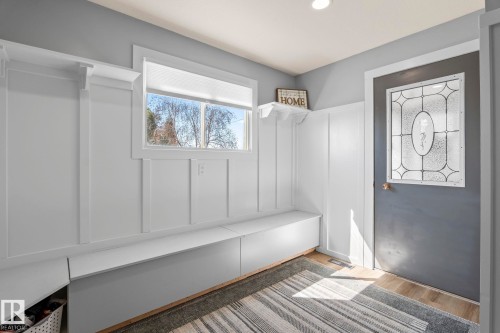 Entryway featuring board and batten detailing, built-in bench seating, integrated storage, and wood-finish flooring - 23133 Twp Rd 502, Rural Leduc County, AB - Indoor Photo Showing Other Room