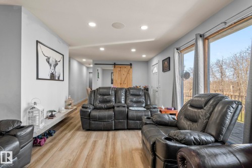 Bright living area featuring wood-finish flooring, recessed lighting, and a large glass door leading to an outdoor deck - 23133 Twp Rd 502, Rural Leduc County, AB - Indoor Photo Showing Living Room