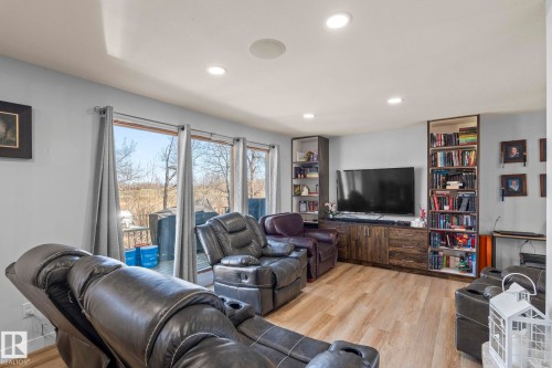Living area featuring wood-finish flooring, recessed lighting, and a wall of windows - 23133 Twp Rd 502, Rural Leduc County, AB - Indoor
