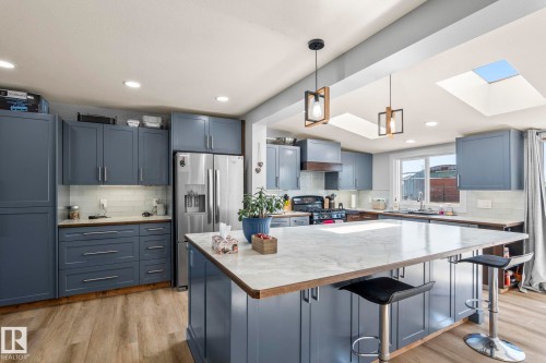 Kitchen featuring blue cabinetry, stainless steel refrigerator, white subway tile backsplash, and light wood-finish flooring - 23133 Twp Rd 502, Rural Leduc County, AB - Indoor Photo Showing Kitchen With Upgraded Kitchen