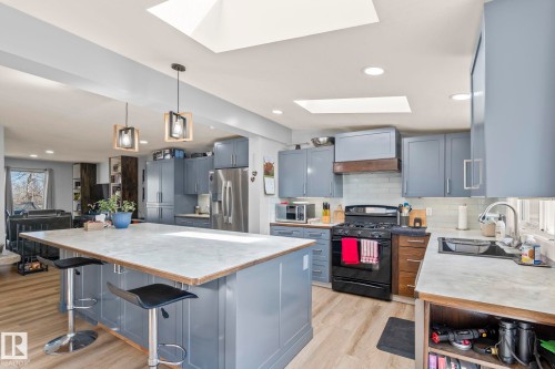 Modern kitchen featuring a large central island with seating, pendant lighting, and skylights - 23133 Twp Rd 502, Rural Leduc County, AB - Indoor Photo Showing Kitchen With Upgraded Kitchen