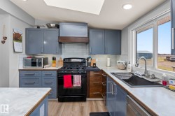 Modern kitchen featuring blue cabinetry, light wood-finish countertops, white subway tile backsplash, and stainless steel appliances - 