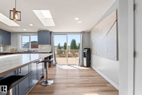 Kitchen featuring blue cabinetry with white countertops, white tile backsplash, and a central island with bar seating - 23133 Twp Rd 502, Rural Leduc County, AB - Indoor